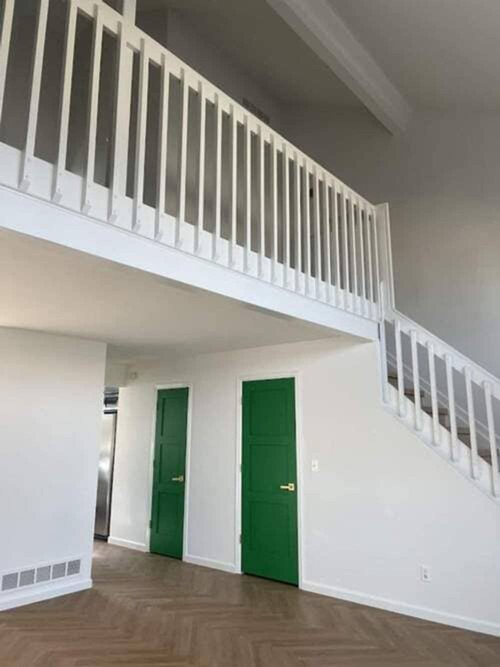 Modern interior featuring a white staircase, green doors, and open space design.
